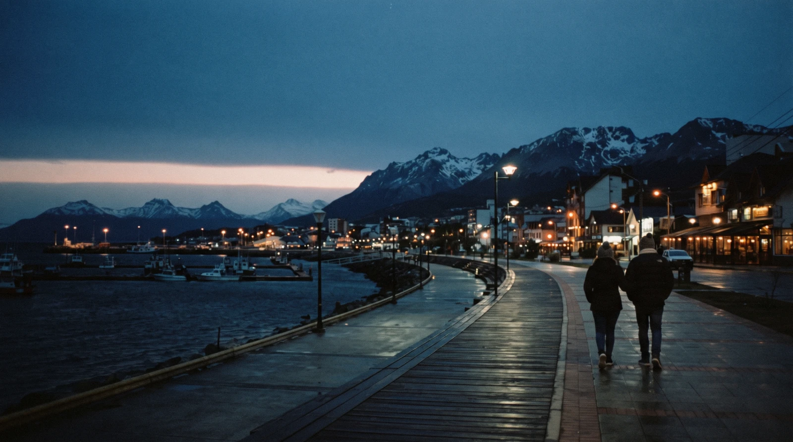 Ushuaia at night, with lit windows along the waterfront and the dark outline of the Martial mountains above the town.